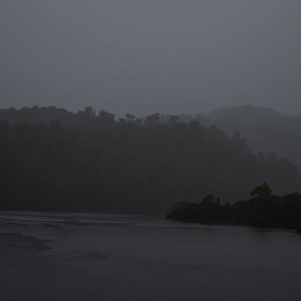 A dark, rainy image of a body of water surrounded by the wilderness